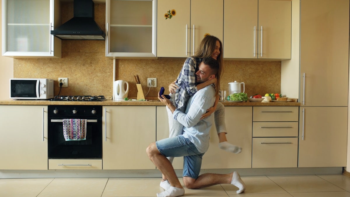 Young man making proposal to his girlfriend in the kitchen at home in the morning